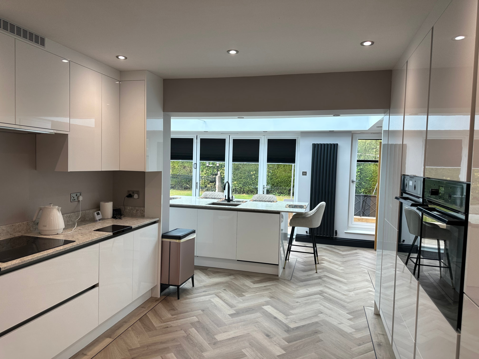 Open-plan kitchen with handleless cabinetry opening into the orangery