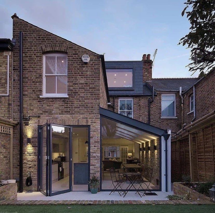 The extension glowing at dusk with doors folded back to the garden