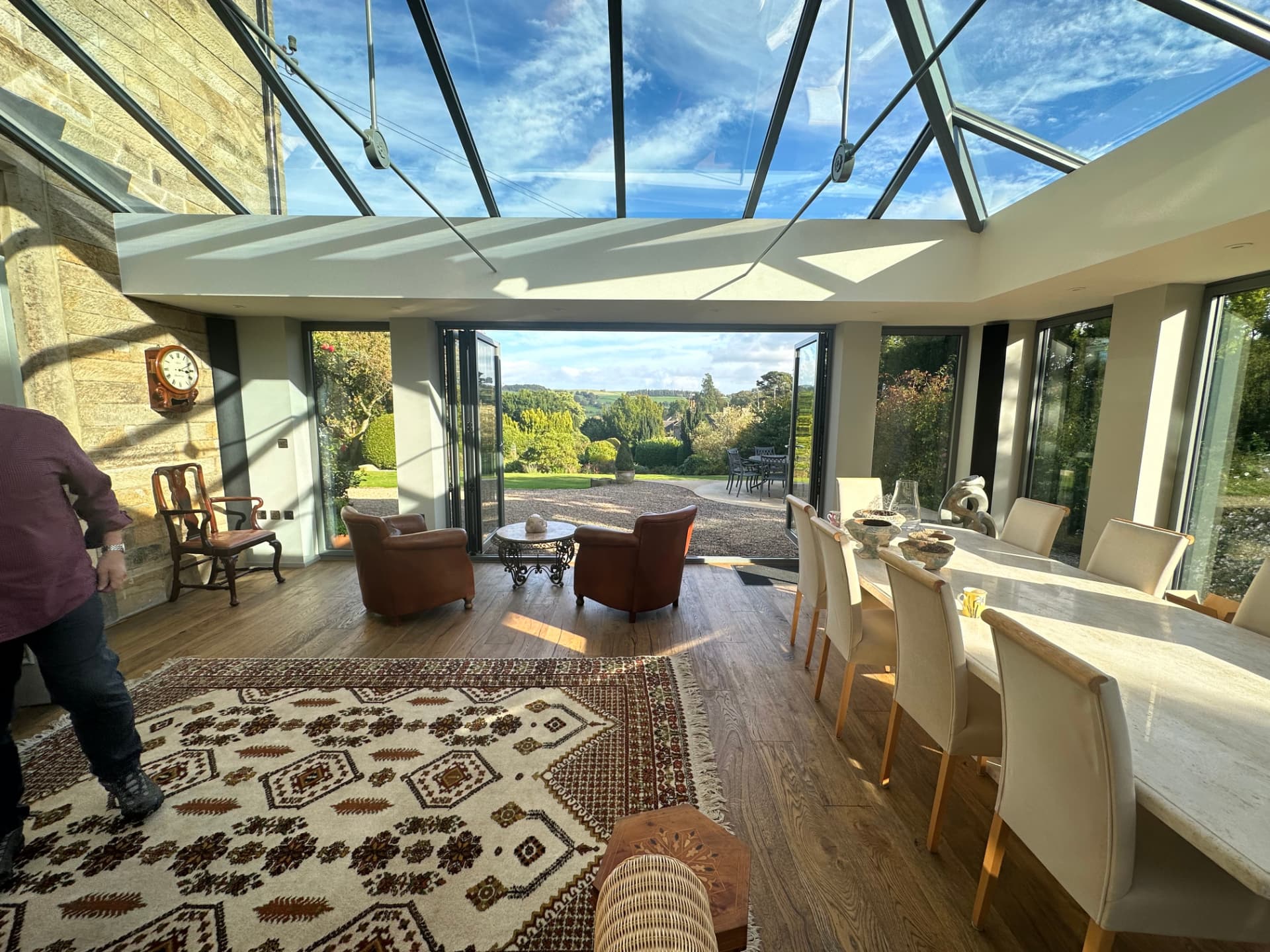 Interior of the orangery with glazed lantern roof, dining table and open bi-fold doors