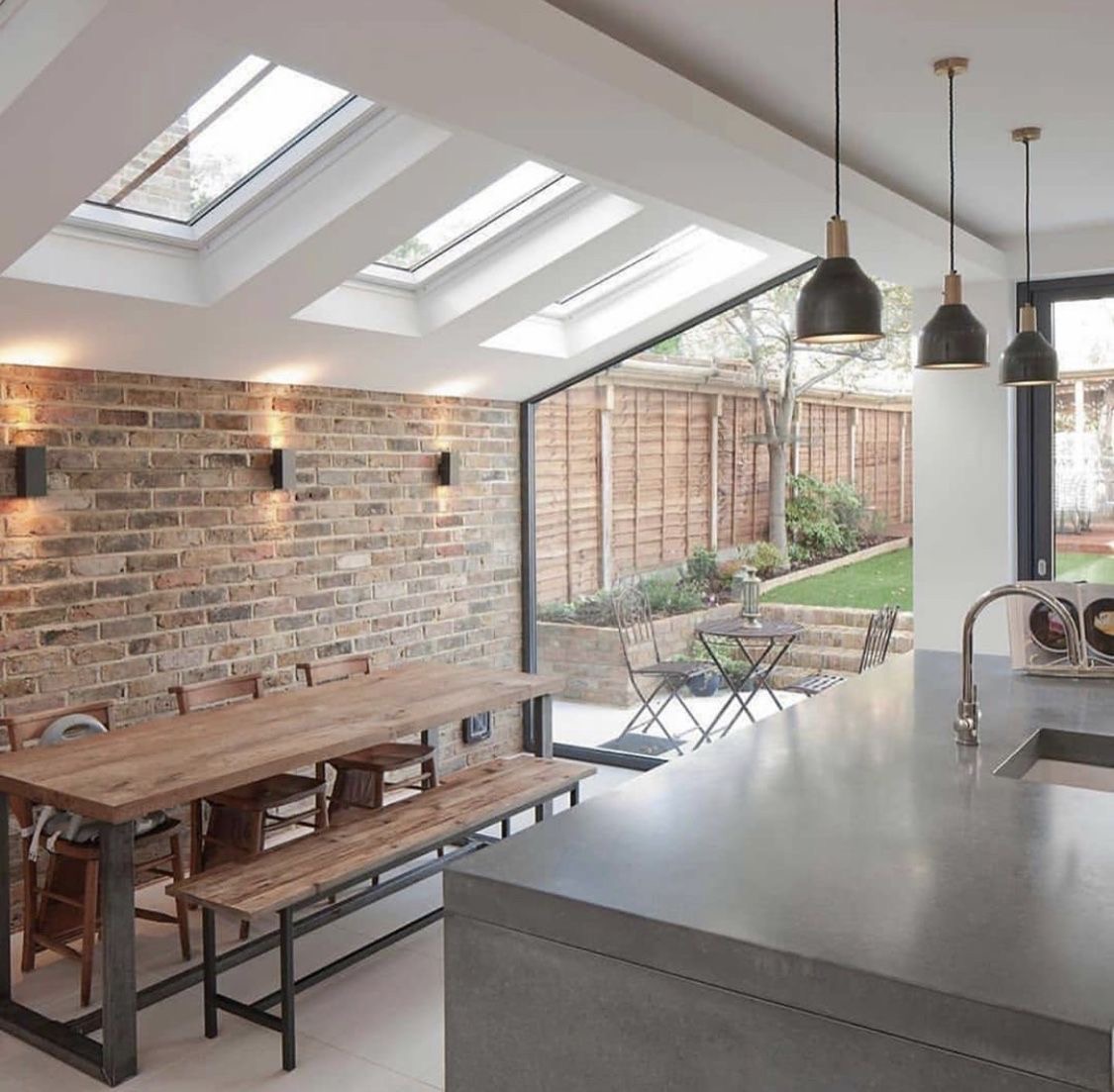 Exposed brick feature wall and dining area beneath roof lanterns