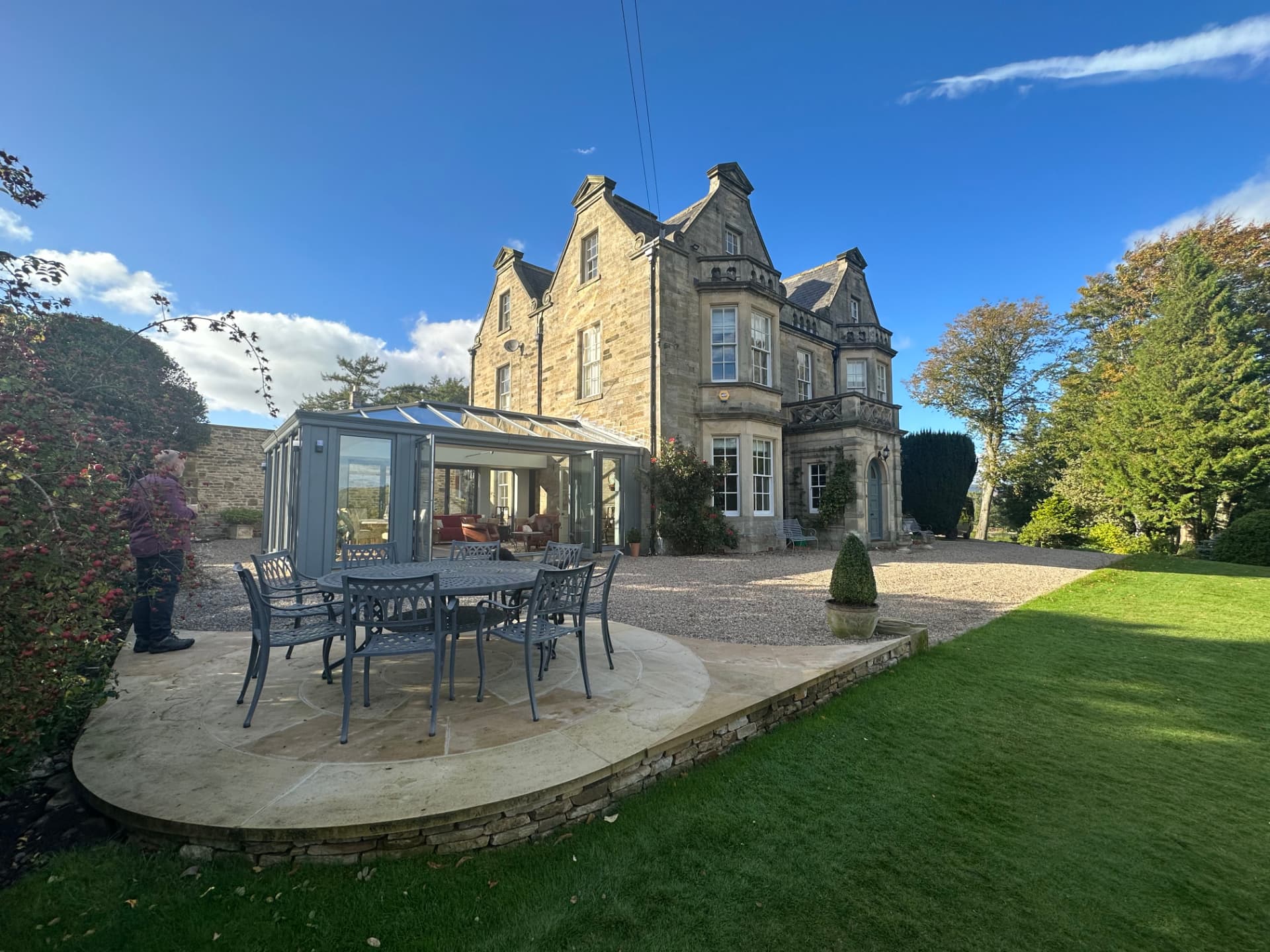 Heritage grey aluminium orangery beside the listed stone house with garden terrace