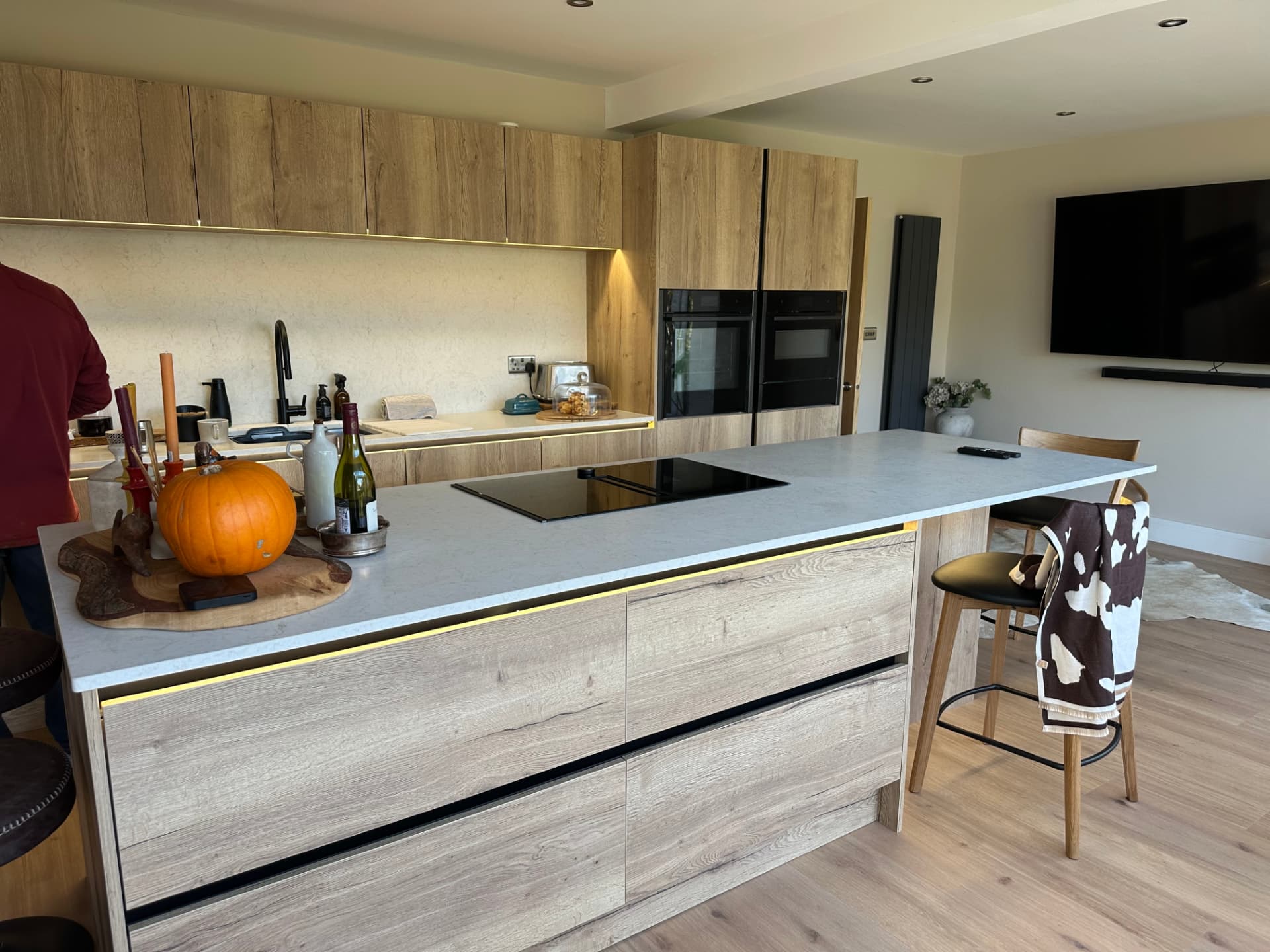 Handleless oak kitchen with quartz island and integrated ovens