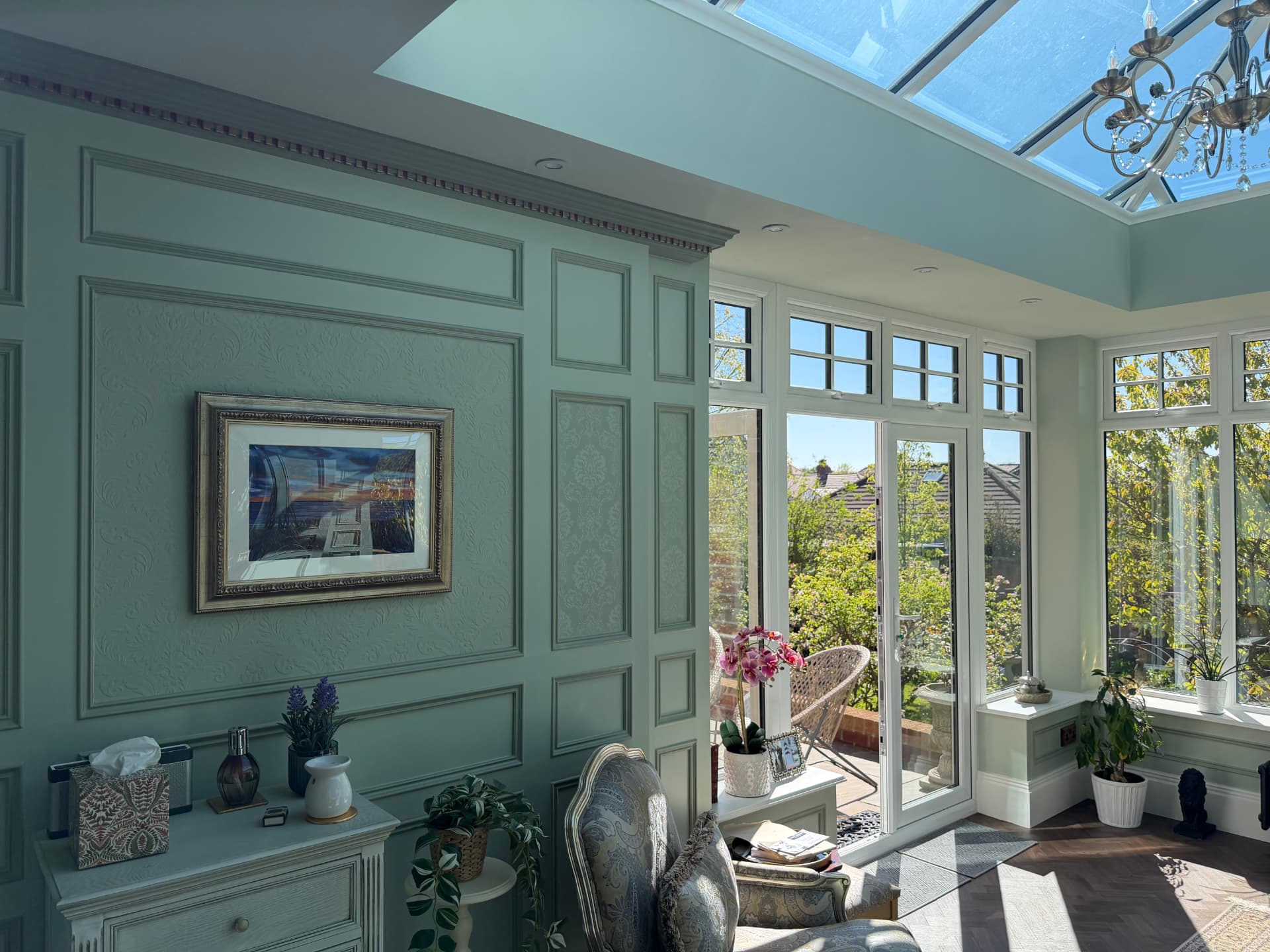 Panelled orangery walls in soft sage with French doors to the garden