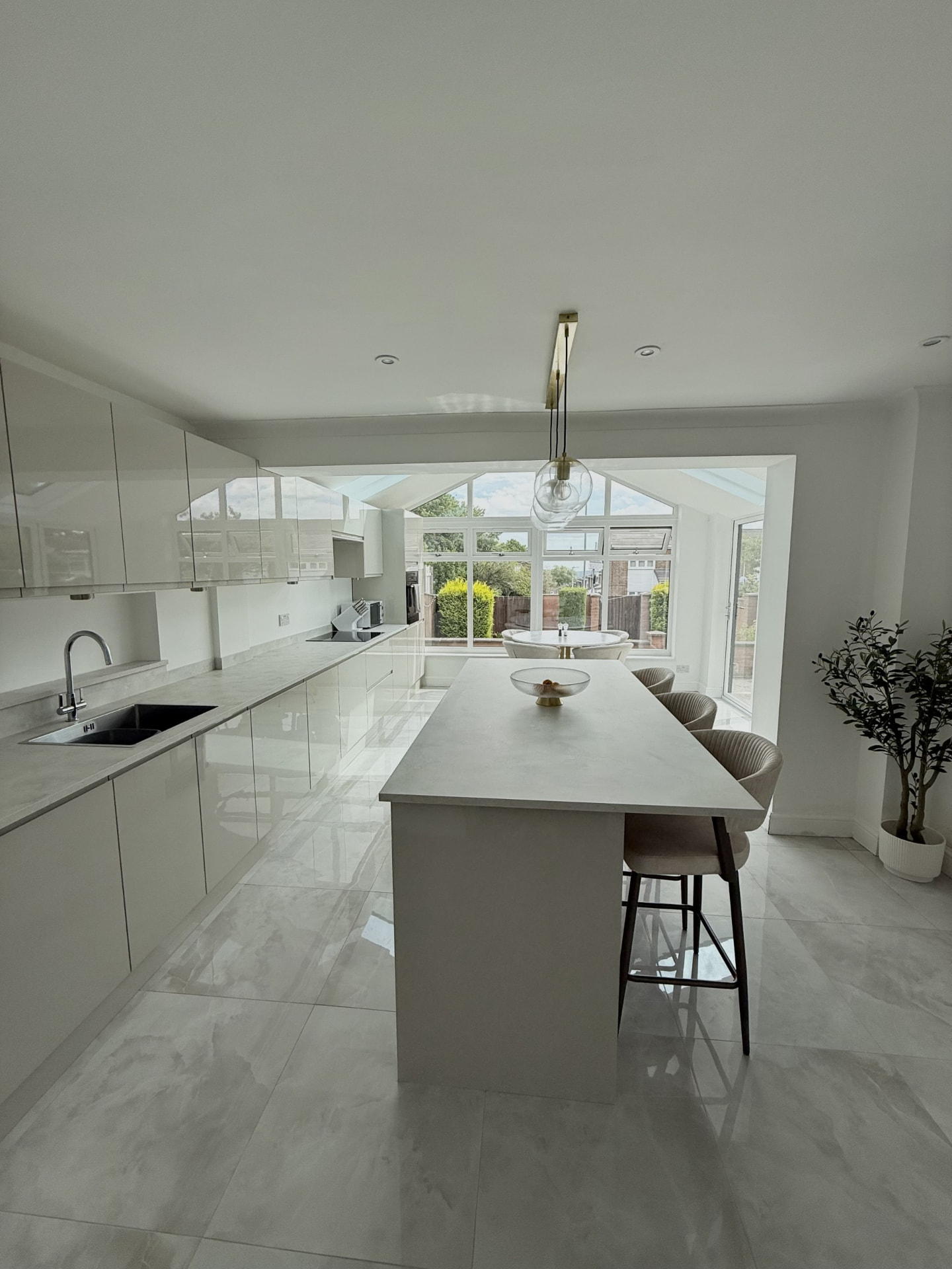 Handleless gloss kitchen with quartz island looking through to the converted conservatory in Stanhope