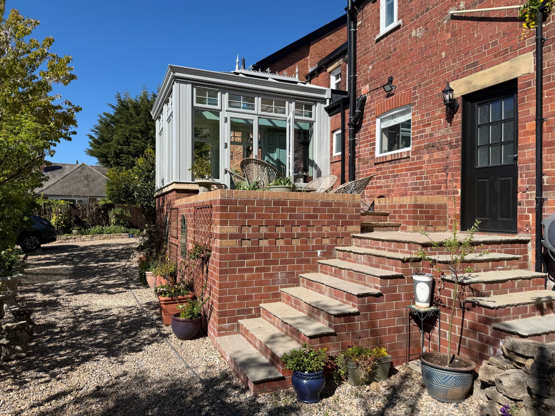 Orangery exterior viewed from the garden with brick steps and planting