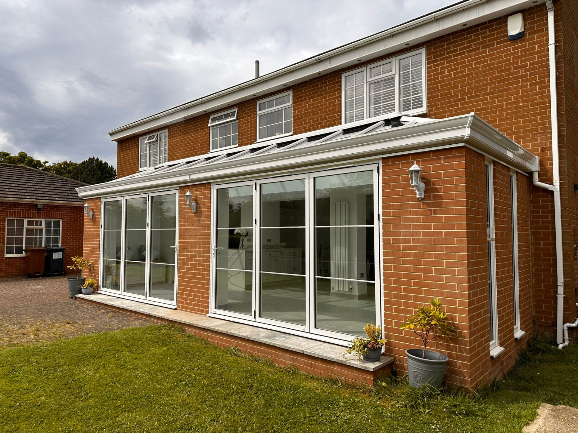 Exterior of brick orangery extension with two sets of white bifold doors